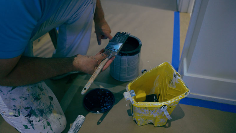 Painter holding a paint brush getting ready to paint a wall