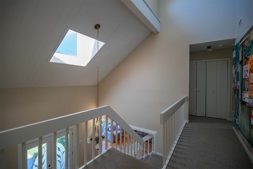Freshly painted staircase landing and upper hallway with neutral wall colors, skylight, and bright natural light in a Bucks County, PA home.