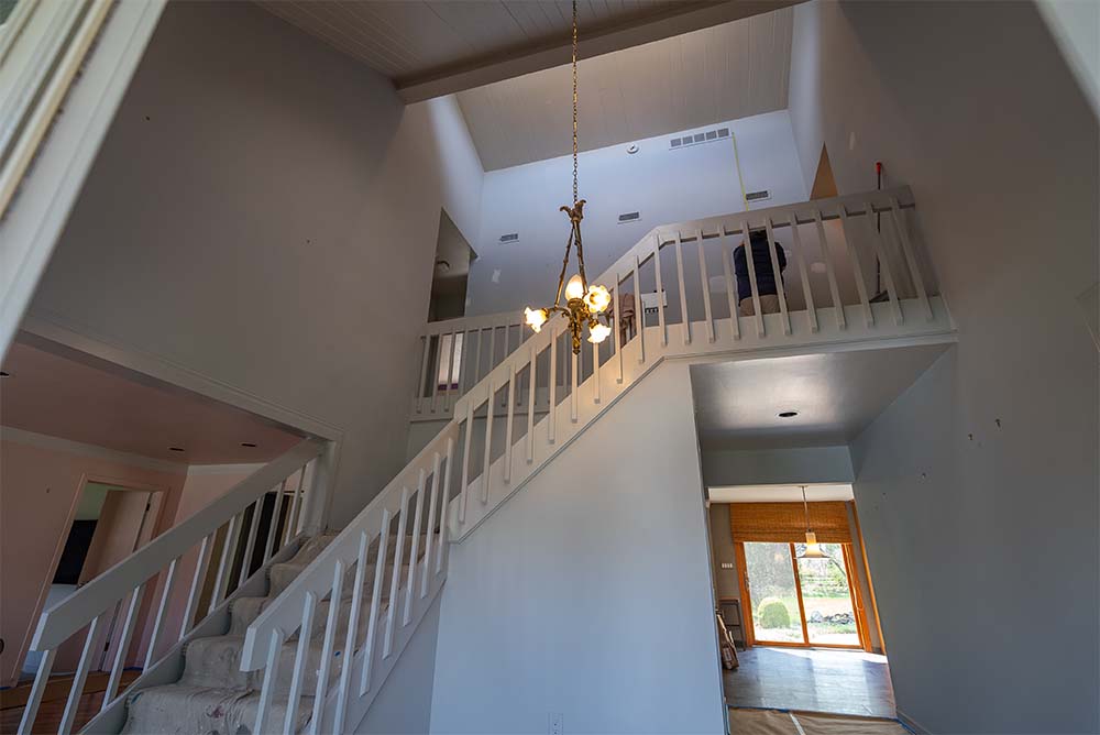 Freshly painted staircase and two-story foyer with modern neutral walls, white trim, and abundant natural light in a Bucks County, PA home.