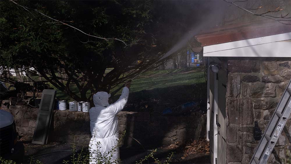 Professional painter pressure washing a home's exterior before painting in Bucks County PA